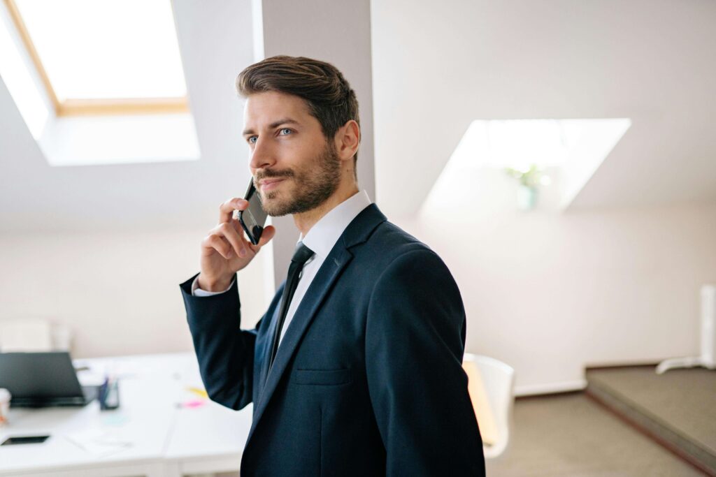 A confident entrepreneur speaking on the phone in a bright modern office, symbolizing success and forward action.